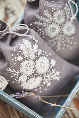 Sachets with embroidery filled with lavender on wooden background