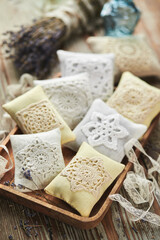 Sachet bags decorated with crocheted lace and lavender on a wooden background