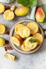 Autumn vegetarian baking. Homemade sweet cottage cheese muffins with pear stuffing, cinnamon and pecan on a stone tabletop. View from above. Copy space.