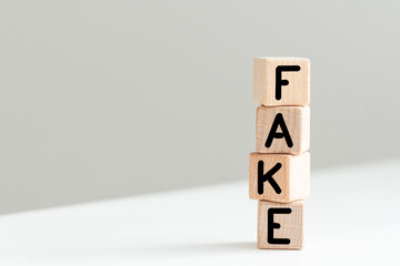 four wood cubes with the word FAKE on the background of white financial statements, strong business concept. gray background