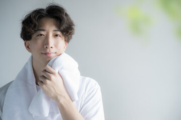 Handsome camera-ready man wiping his face with a towel Image of training and face washing