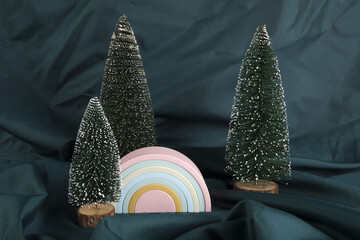 a plastic rainbow toy amid a forest of miniature, snow-covered artificial fir