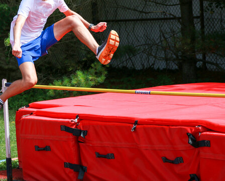 Teenage boy jumping over a high jump bar like he is hurdling