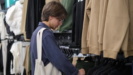 young guy go shopping center. Teen choose casual clothes, Shopper Selecting Stylish Garments