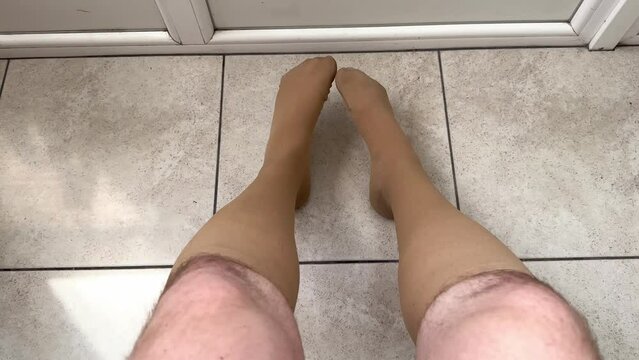 A man's hairy legs are dressed in knee-high compression stockings to prevent varicose veins. Tight stockings are worn on men's legs. Feet in socks