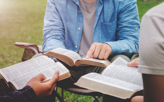 Christian life bible study concept Group of Christian friends sitting together studying the Bible Outdoors in the park and pray together and live according to God's word