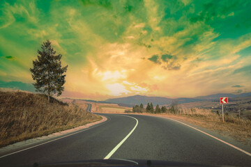 View of the mountain winding road from windscreen during sunrise
