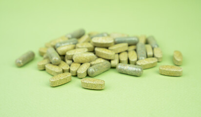 Natural vitamins and supplements on a green background. Close-up. Selective focus.