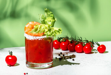 Bloody Caesar cocktail drink, Bloody Mary variation with tomato juice, vodka, clam broth, celery, hot sauce and ice in glass. Green background, hard light