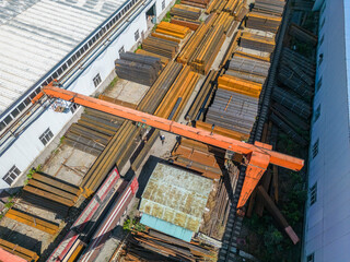 Workers loading stack of metal pipes with gantry crane into the truck