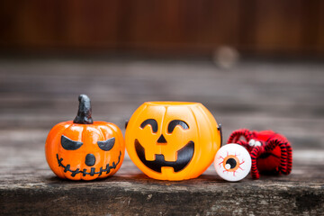 Funny Halloween pumpkin with eyeboll toy and wool spider on wooden floor with space on blurred background, Halloween decoration item
