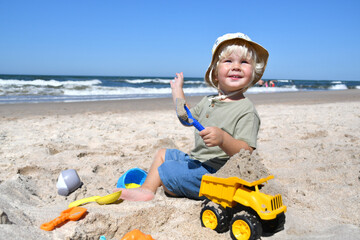 Little happy bpy playing with toys on the beach