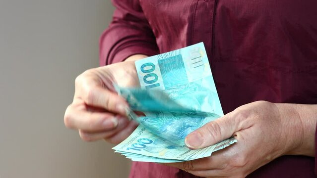 Brazilian money, Woman counts cash, larger sum of money, Brazil reais banknotes, Financial concept