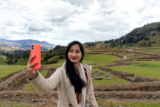 turista joven en las ruinas de ingapirca realizandose una autofoto con su teléfono movil y sonriendo muy alegre en una tarde de primavera en las montañas de los andes 