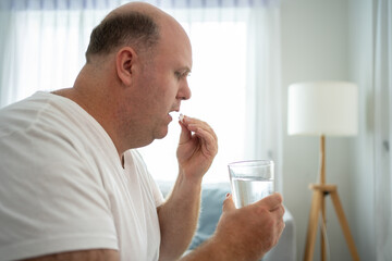 Step into a scene of health and responsibility as a Caucasian man administers his medication,...