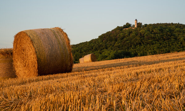 Hay bales under castle Plesse in Bovenden, Germany during sunset.