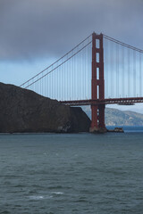 Red metal steel suspension bridge Golden Gate Bridge in San Francisco Bay Area with coast and city...