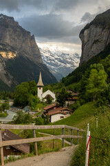 Buildings and a Church Sitting Along the Hills high up in Lauterbrunnen in the Swiss Alps with mountains in the background in Switzerland in Summer
