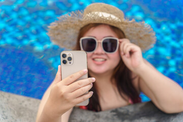 Overweight young woman orange swimsuit relaxing and holding smartphone in swimming pool. Obese Woman Vacation Traveling hand using phone