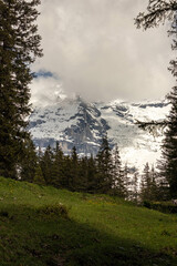 Swiss Alps in Switzerland in the Summer with Mountains Peaking Through Clouds in the Background