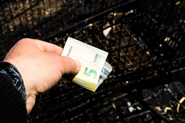 Coin and banknotes on black hot coal among ashes. Currency devaluated, finance and business concept