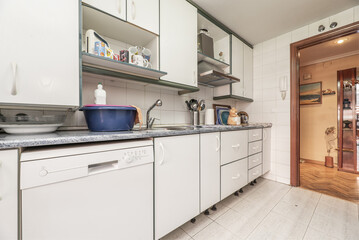 Kitchen furnished on both sides of the wall with white furniture with white metal handles,