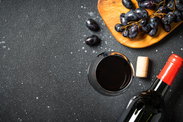 Red Wine at black background. Glass of wine, bottle and crape. Top view with copy space.