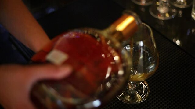 edle Spirituosen in Glas an Bar einschenken / Barkeeper / Whisky / Alkohol / edler Tropfen /