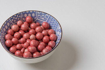 Chocolate candies in a bowl on a white table.