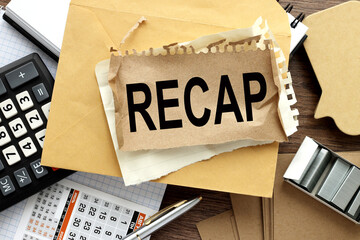 Recap text on torn paper. wooden background. office supplies