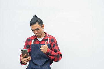 Asian young man Wearing a red and black plaid shirt, wearing a denim apron. happy with the deal