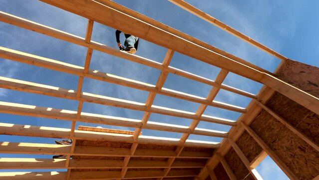 Time lapse of carpenters mounting OSB panel on the roof of future cottage. Men workers building wooden frame house. Carpentry and construction concept.