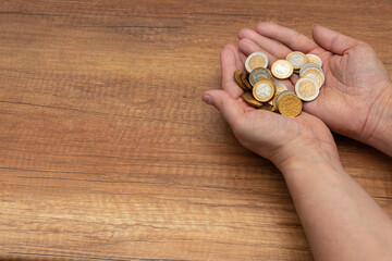 Hands holding coins in gold denominations. The concept of deferring for worse times and for retirement.  