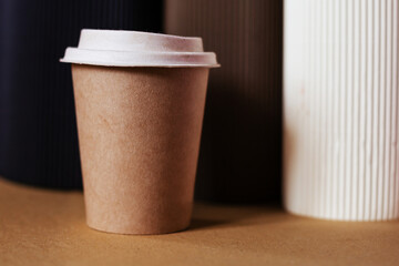 Brown coffee cup with a white lid on a craft background. Creative background with space for text to advertise coffee and beverages