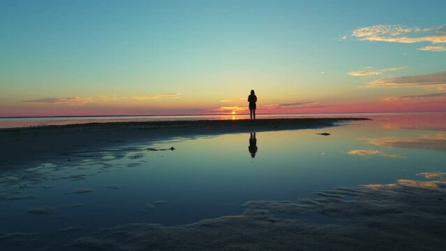Romantic woman watching at beautiful sunset on the lake, lake with sunset, mirror reflection of the sunset on the lake pink and turquoise sunset