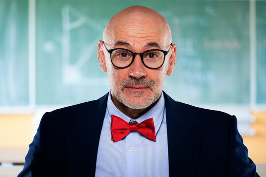 Surprised mid aged professor standing in front of blacboard in the classroom