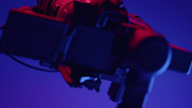 fully rigged dslr video camera on a electronic 3-axis gimbal moving around on blue background. Modern filmmaking device for stabilized shots