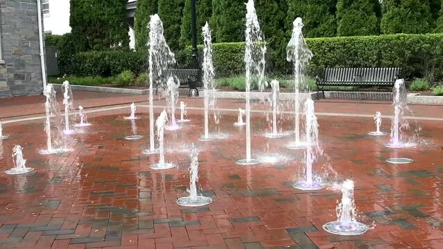 Fountain jets on the sidewalk. Water squirts from a floor fountain. Slow motion.
