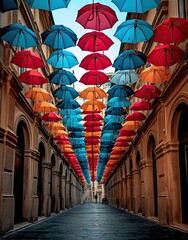 many colorful umbrellas hanging from the ceiling in an old city street lined with stone buildings and cobbed streets