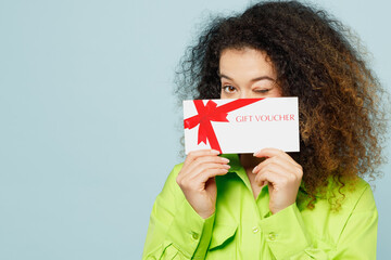 Young happy latin woman wear green shirt casual clothes hold cover mouth with gift certificate...