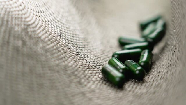 Herbal green capsules of alternative herb medicine with Ginkgo biloba extract. Natural health supplement pills. Falling in slow motion close up