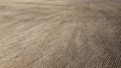An aerial perspective unveils a plowed farm field with the backdrop of rich black soil.
