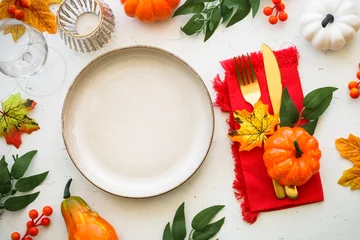 Foto op Aluminium Autumn table setting at white kitchen table. Craft plate, golden cutlery and fall decorations with pumpkins and leaves. Flat lay image with copy space. © nadianb