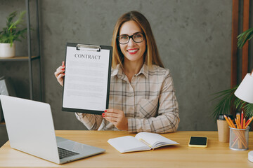 Young successful employee business woman wear shirt casual clothes glasses sit work at office desk...