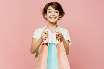 Young surprised shocked woman wear casual clothes hold shopping paper package bags look camera show...