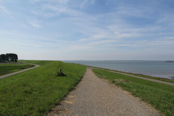 a road op top of the seawall in front of the westerschelde sea at the dutch coast in zeeland and a blue sky