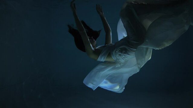 Plunging girl to fall under water Slow motion. Girl swimming under water in basin. Woman dives in the pool.