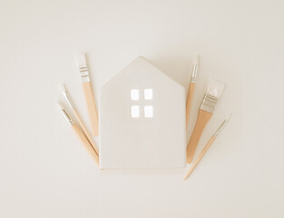 A white house with brushes on a white background. Choice of colors and design for the home. Home renovation concept.