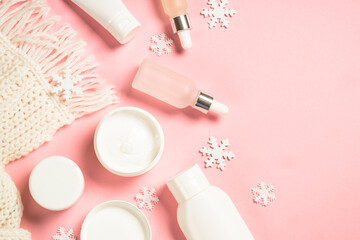 Winter cosmetic at pink background. Cream, serum and knitted scarf. Top view with copy space.