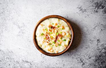 Fresh hot chowder soup with fried bacon slices and shredded cheese in a bowl